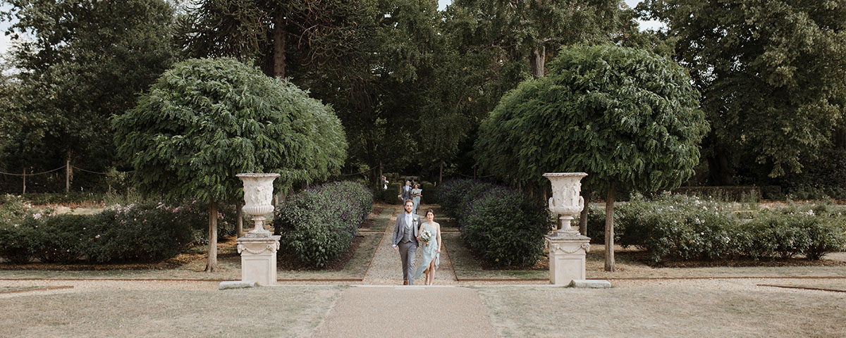 Wedding guests happily walking up to the wedding venue through a garden