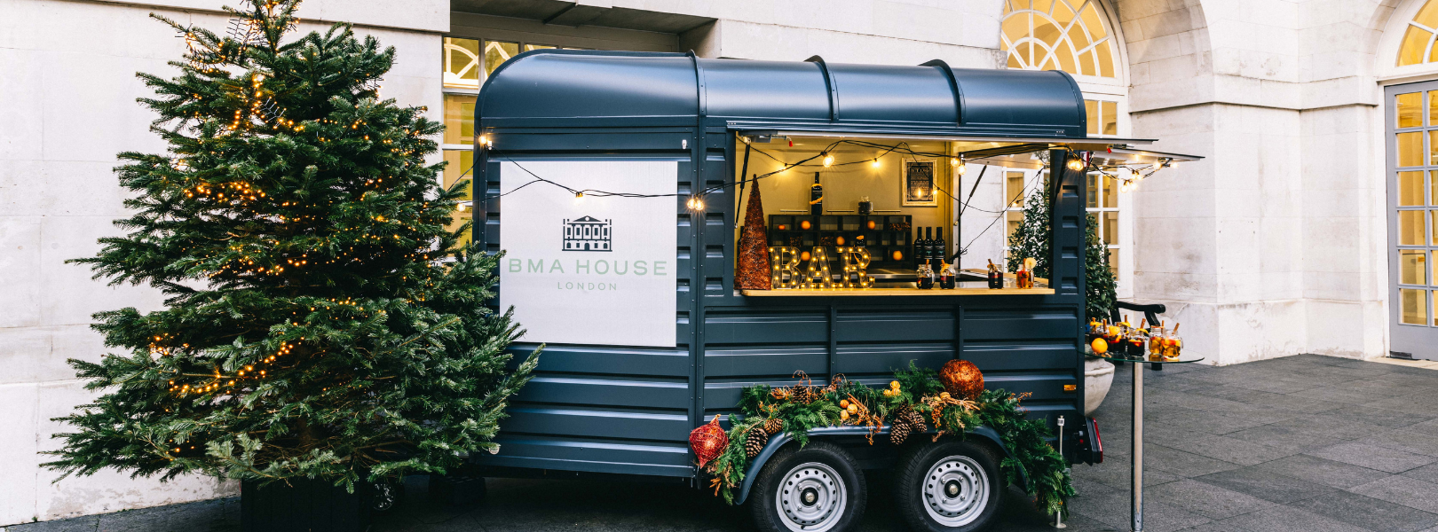 a christmas booth serving up drinks and food ahead of a corporate christmas party which is outdoors