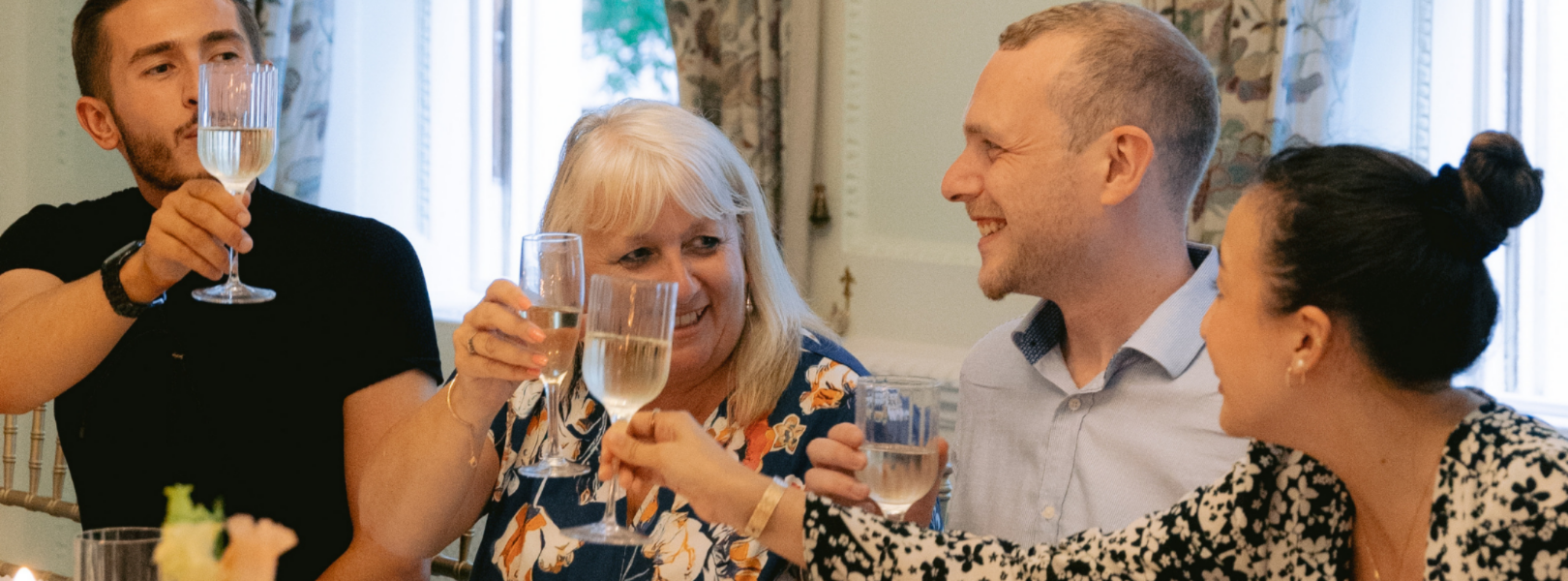 people cheering and lifting their drinks to celebrate christmas at a dinner table