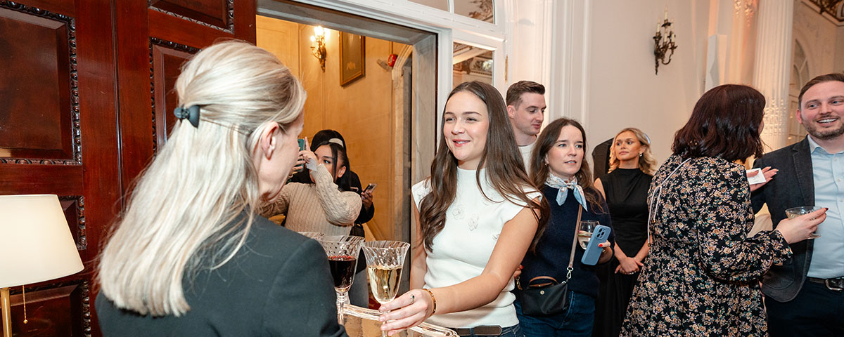 someone picking up a glass of champagne from a tray at an event