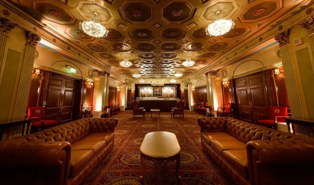 Wide room with long leather sofas and red printed carpet