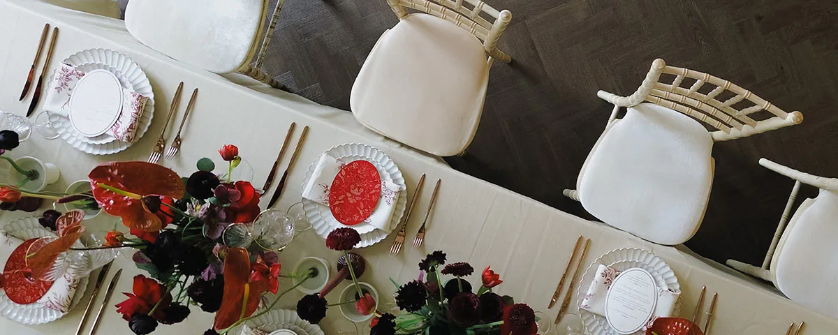 Birdseye view angle of a table spread ready for a wedding day meal. Table spread is decorated with flowers and gold cutlery
